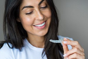 Happy woman looking at her Invisalign aligner