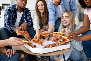 Group of young adult friends eating pizza together