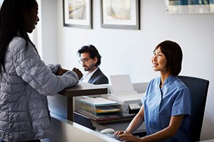 Dental team member interacting with patient at front desk