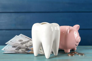 piggy bank, tooth model, and money against simple background