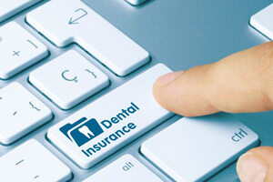 finger pressing dental insurance key on computer keyboard