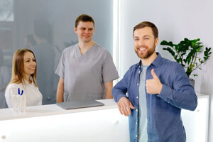 patient at dental office front desk, making thumbs up gesture