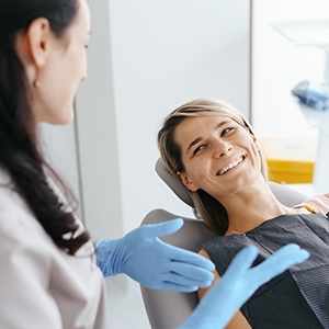 Happy patient in treatment chair interacting with dental team member