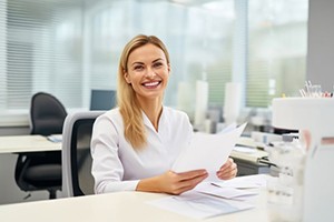 Friendly dental team member holding paperwork