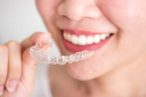 Woman holding Invisalign aligner close to her teeth